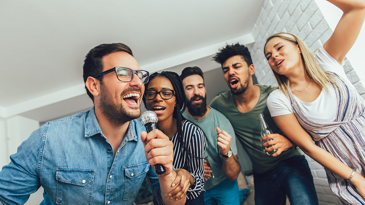 Grupo de amigos cantando karaokê em casa com microfone